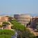 The Colosseum surrounded by trees and other buildings in Rome, Italy